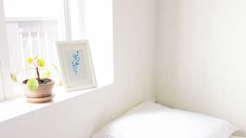 Un coin de pièce avec un lit, une fenêtre et une plante en pot.
