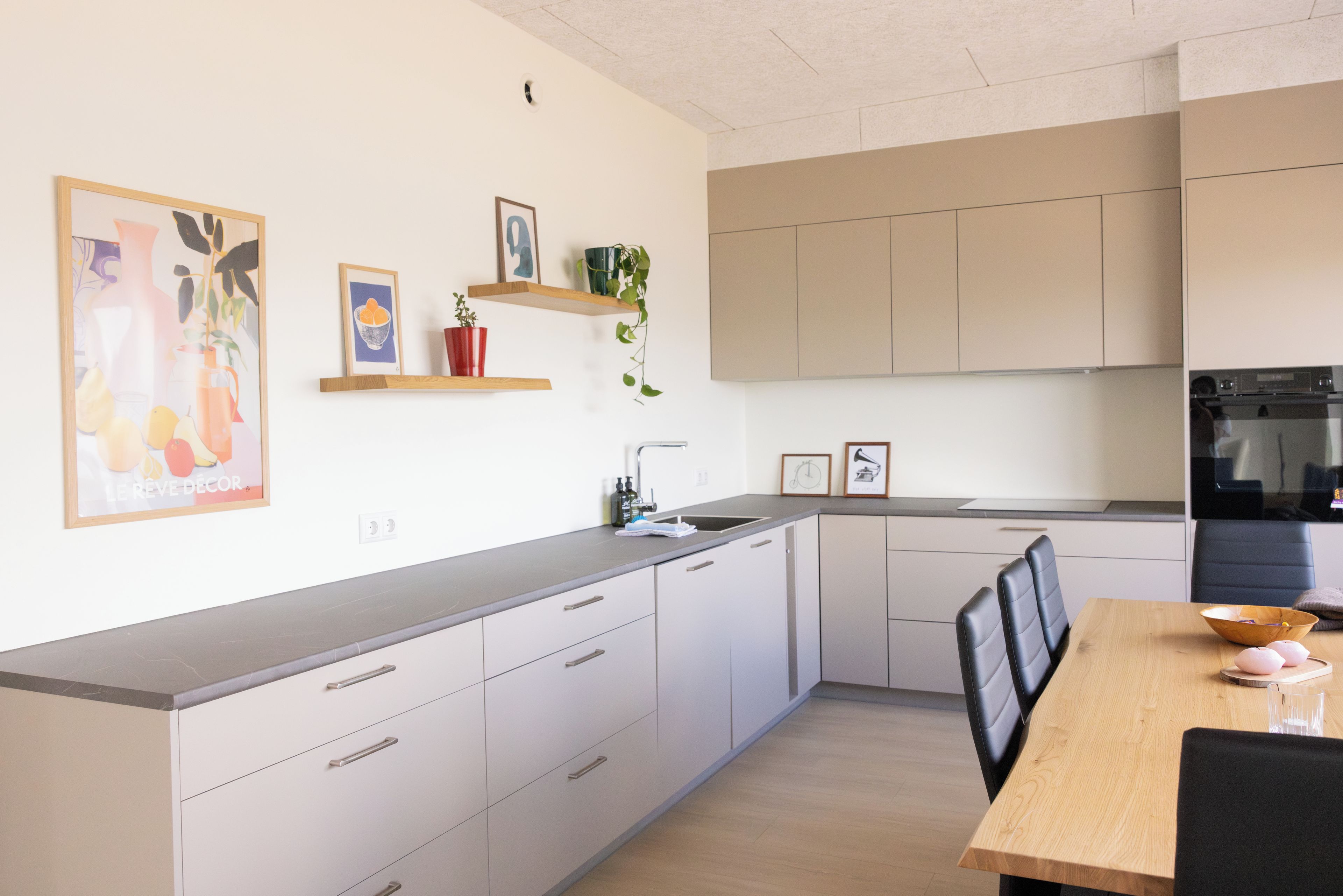 Una cucina moderna con mobili bianchi, un piano di lavoro in legno e un'area pranzo con tavolo e sedie.