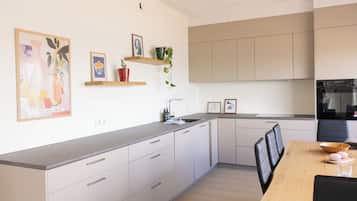 Una cucina moderna con mobili bianchi, un piano di lavoro in legno e un'area pranzo con tavolo e sedie.