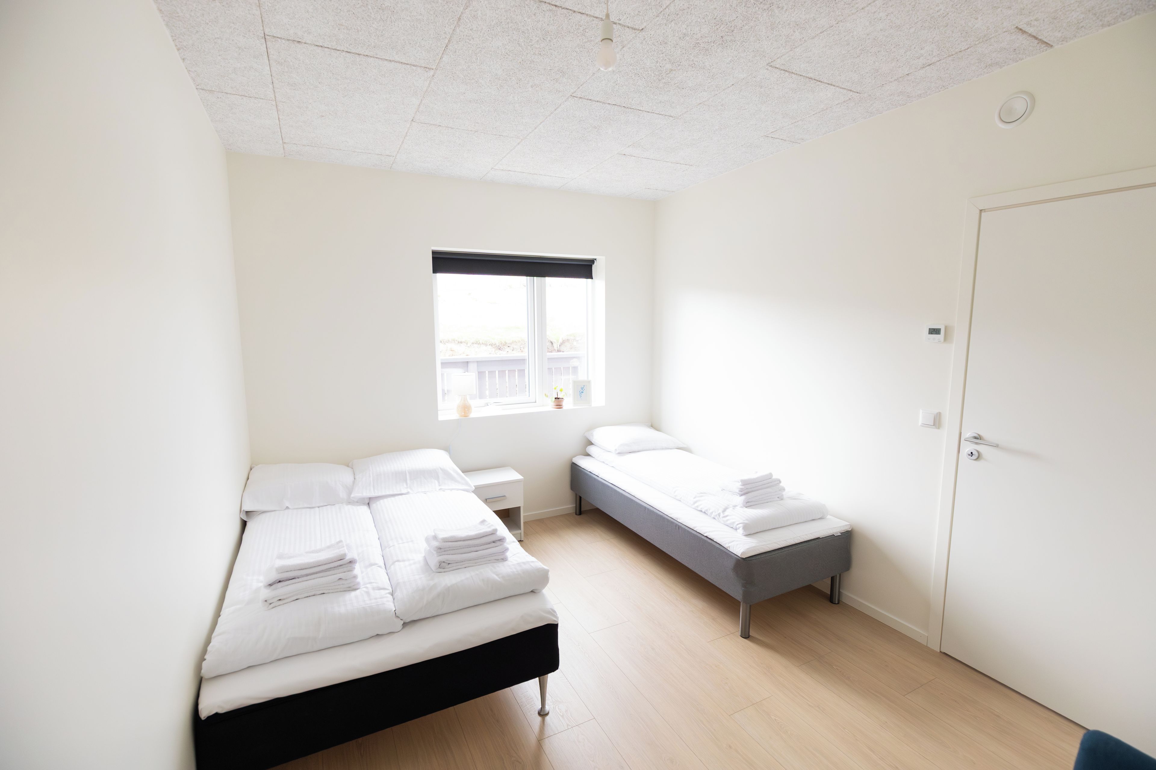 Una camera da letto minimalista con due letti, una finestra e una porta.