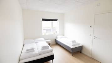Una camera da letto minimalista con due letti, una finestra e una porta.