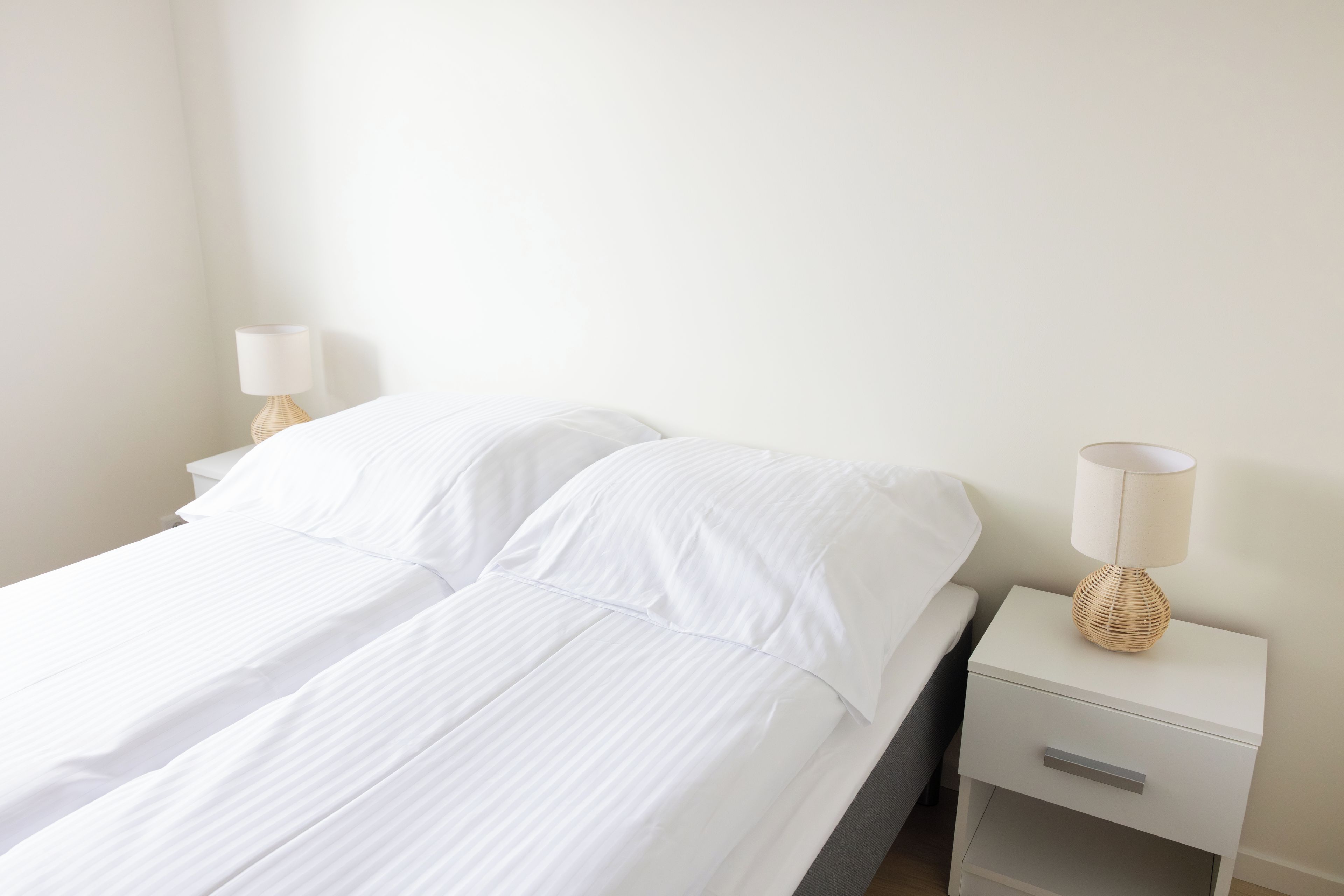 Una habitación sencilla y limpia con una cama, dos mesitas de noche y una lámpara.