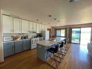 A modern kitchen with a central island, built-in appliances, and a view of a lake through large windows. - Serene 3-bedroom house in Pagosa Springs perfect for your getaway (Pagosa Springs)