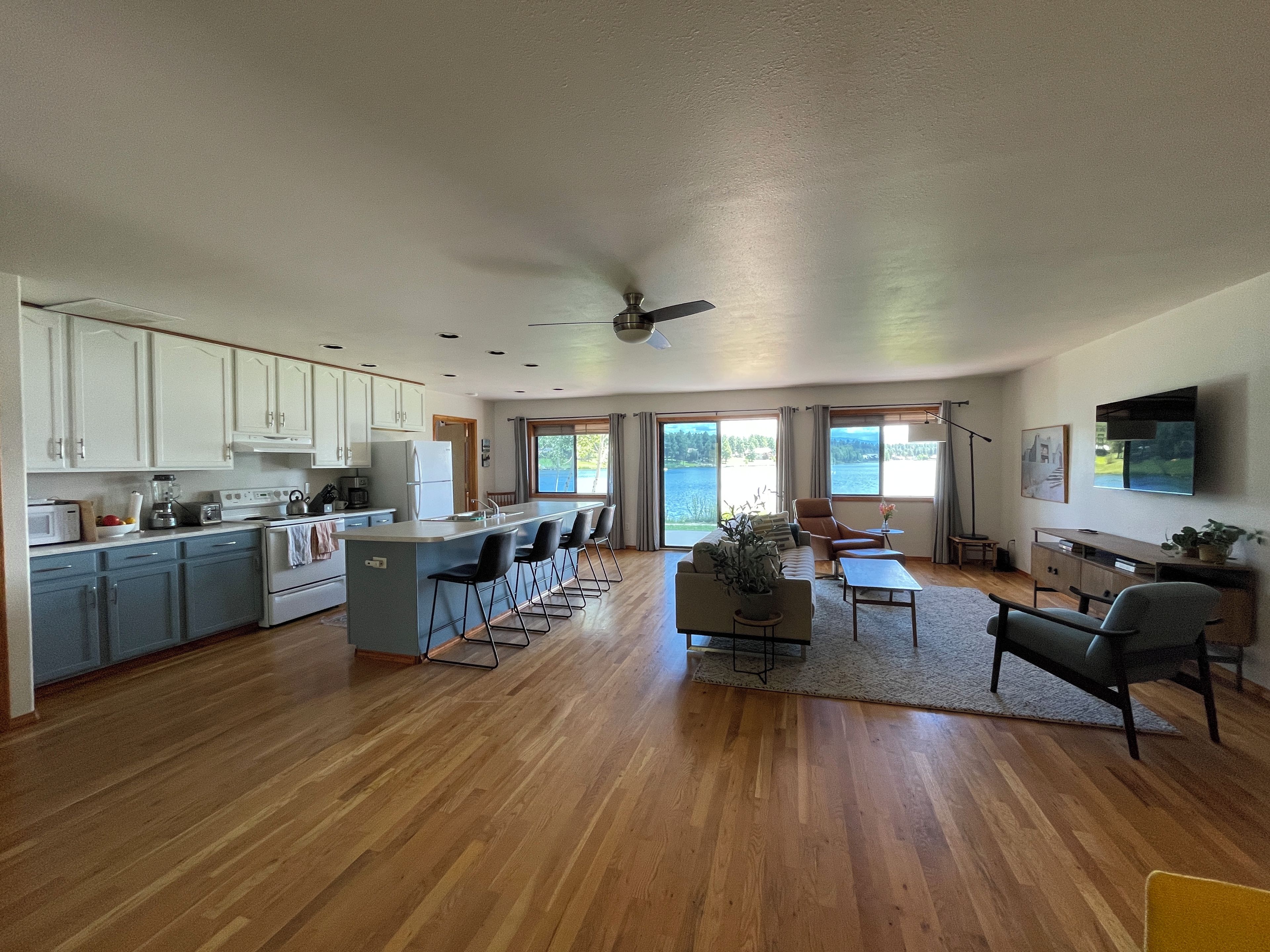 A spacious living area with a kitchen, a dining area, and a large window offering a view of the outdoors.