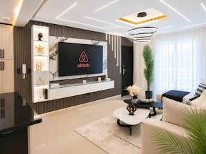 A modern living room with a mounted flat-screen TV, a coffee table, a sofa, and a potted plant. - Modern Luxury • Gym • Fast WiFi • Parking (Santiago De Los Caballeros)