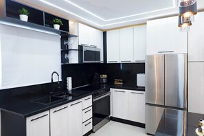 A modern kitchen with white cabinets, black countertops, stainless steel appliances, and a pendant light. - Modern Luxury • Gym • Fast WiFi • Parking (Santiago De Los Caballeros)
