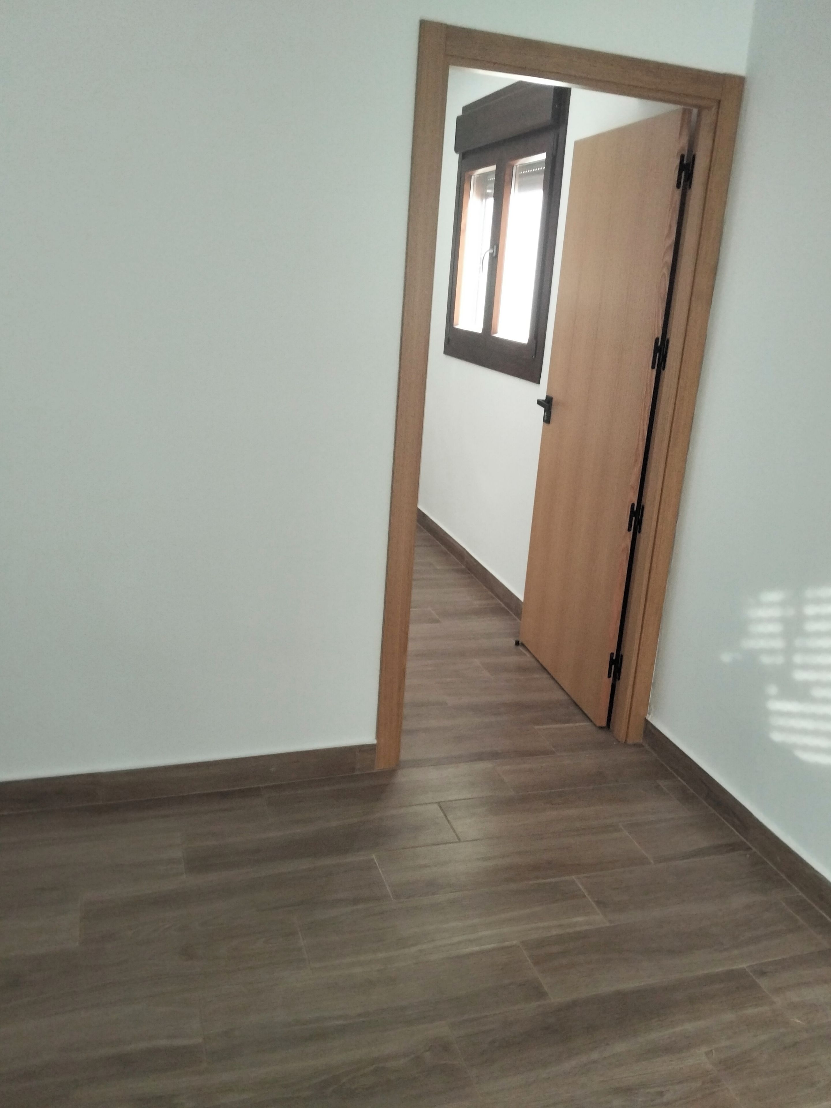 Un couloir avec une porte en bois et une fenêtre.