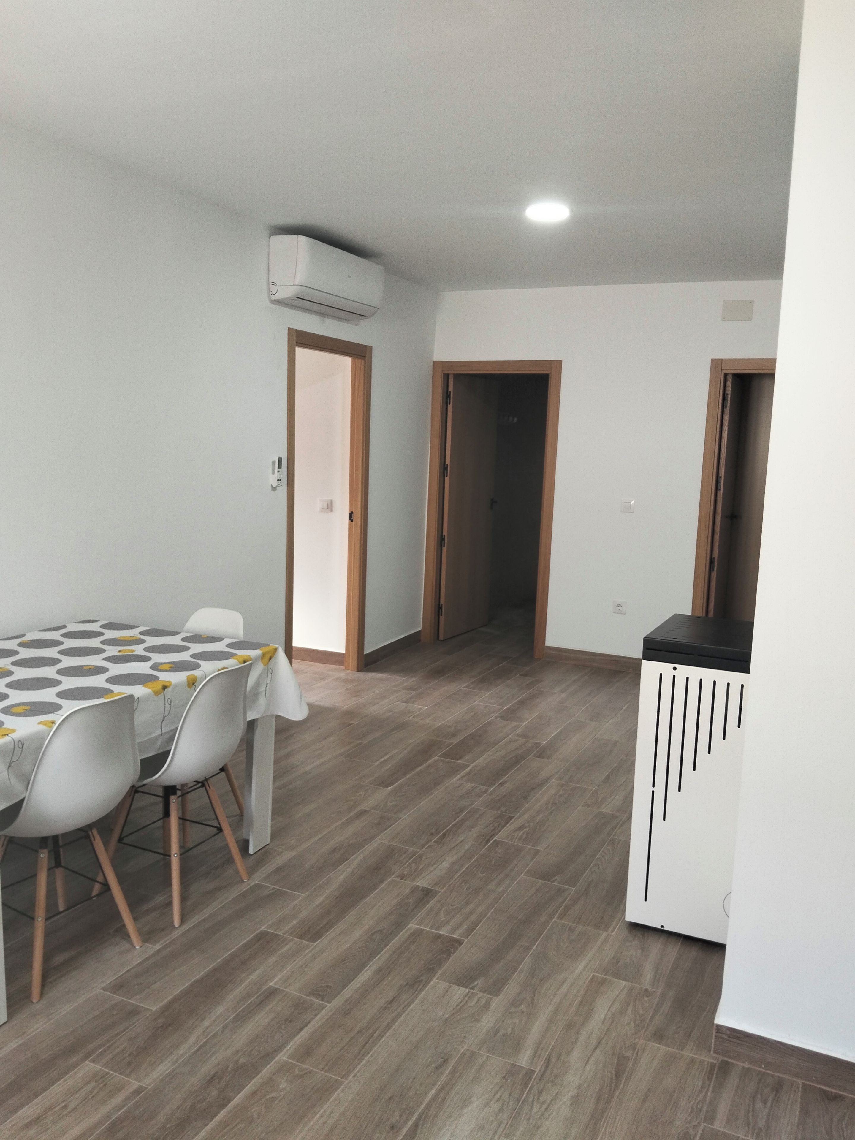 Un coin repas avec une table et des chaises, une kitchenette et un couloir menant à une autre pièce.