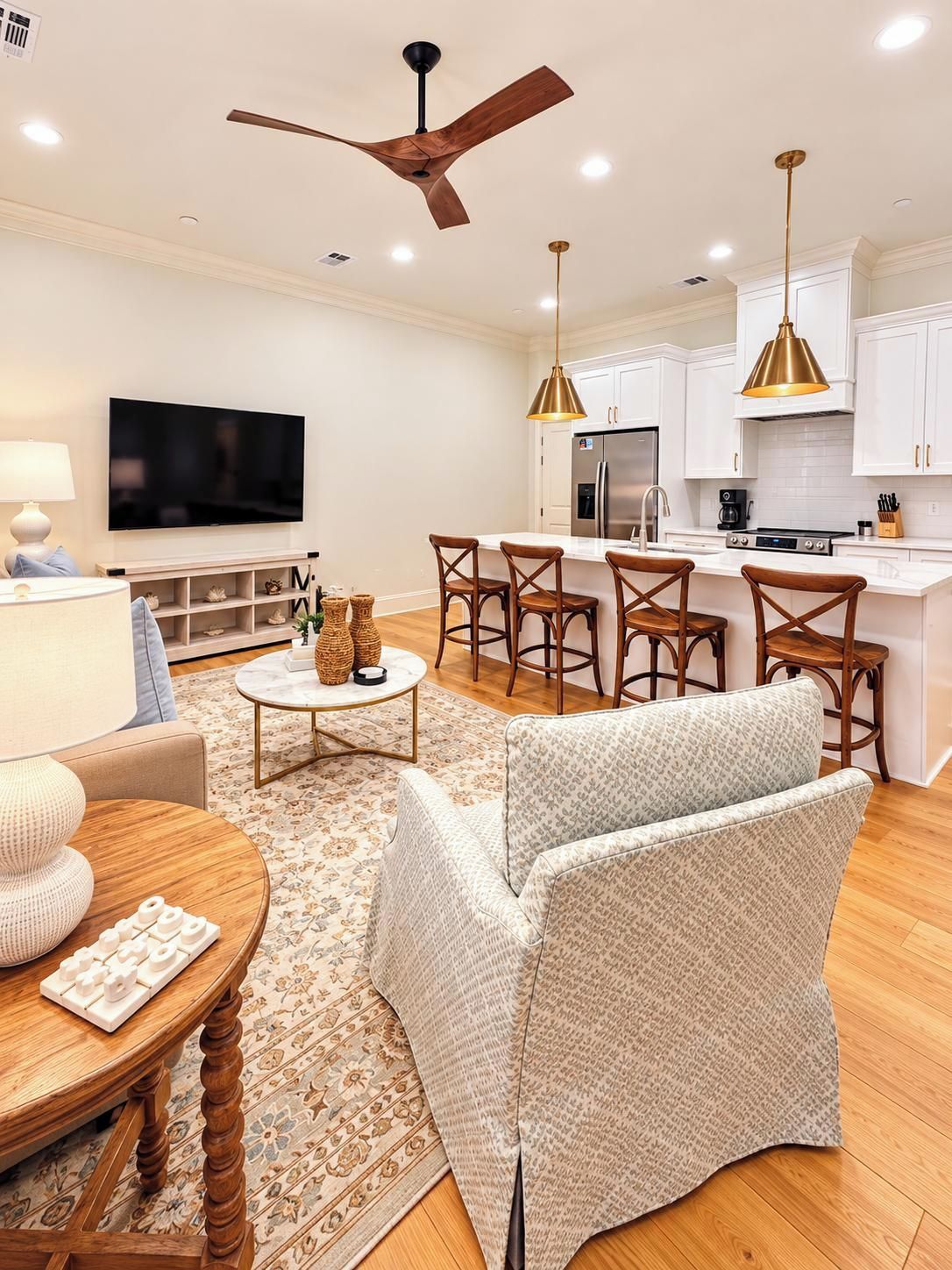 A modern living room with a TV, seating, a coffee table, and a kitchen area with a fridge and stove.