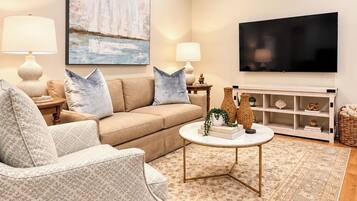 Un salon comprenant un canapé, un fauteuil, une table basse et un téléviseur à écran plat.