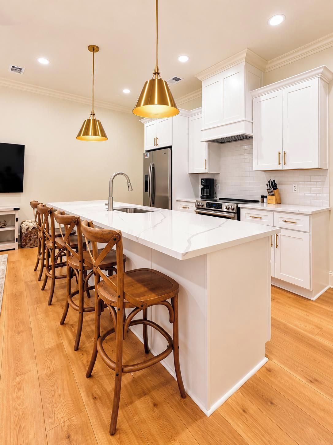 A modern kitchen with white cabinetry, a central island with bar stools, stainless steel appliances, and pendant lighting.