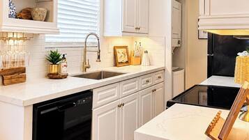 A modern kitchen with white cabinetry, a black dishwasher, and a black stove.