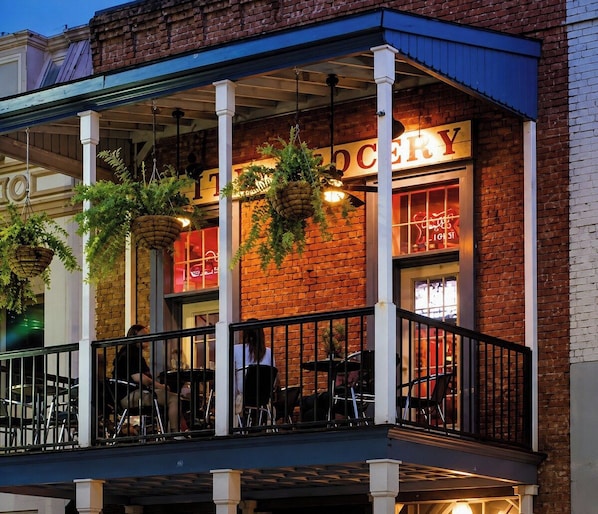 A brick building with a sign that reads 'TOILETRY' and a balcony with hanging plants.