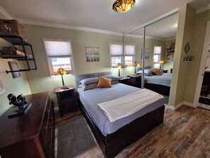 Ein Schlafzimmer mit einem großen Bett, Nachttischen, Lampen, einem Spiegel und einem Kleiderschrank.