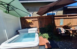 Ein Garten mit Whirlpool, Terrassenmöbeln und einem Holzzaun.