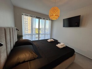 A modern bedroom with a bed, a TV, and a balcony view. - Beautiful, air-conditioned 2-bedroom apartment with a sea view in a quiet neighborhood (Saint Raphaël)