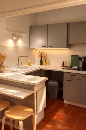 Une cuisine moderne avec des meubles gris, un plan de travail blanc et un petit îlot central doté de tabourets.