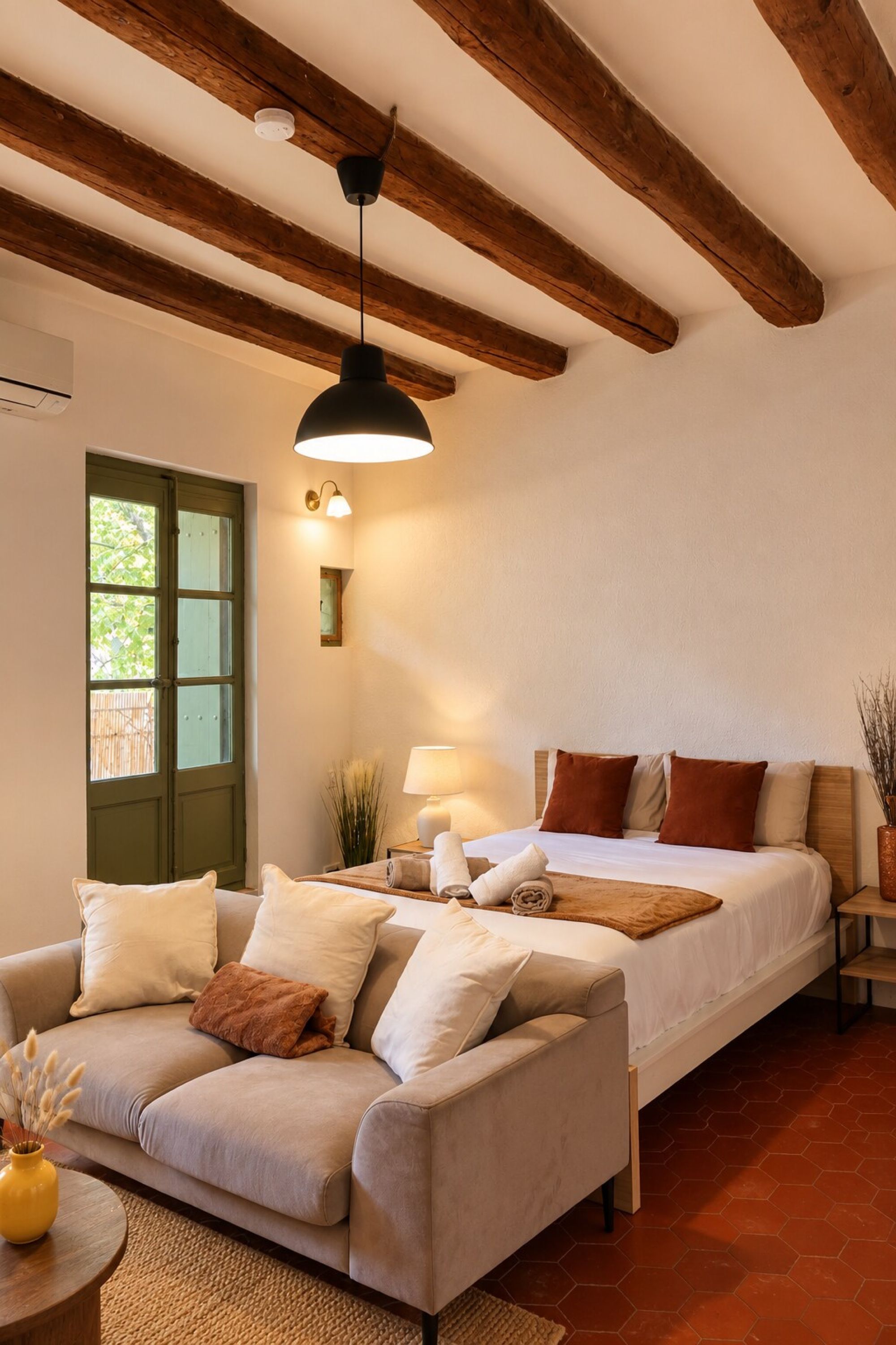 Una habitación con cama, sofá, lámpara y una lámpara colgante.