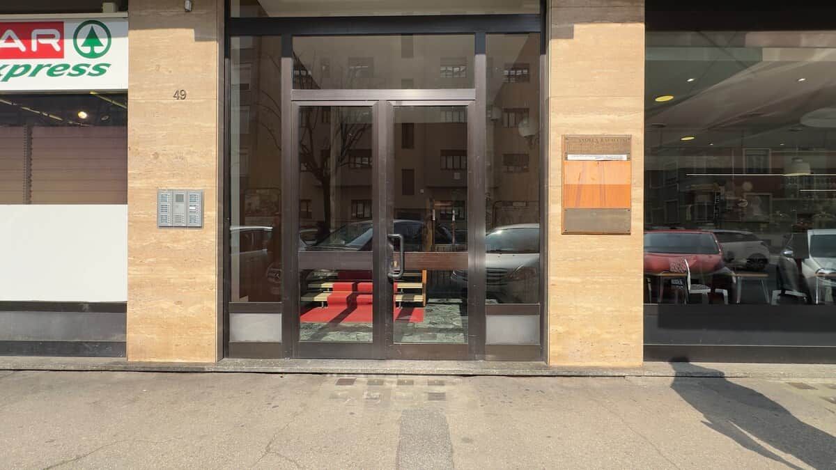A building entrance with a glass door, a visible car parked outside, and a sign for a store named 'AR Express' on the left.