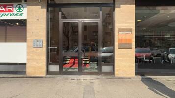 A building entrance with a glass door, a visible car parked outside, and a sign for a store named 'AR Express' on the left.