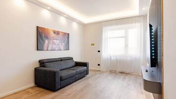 Ein modernes Wohnzimmer mit einer Couch, einem Flachbildfernseher und einem Bild an der Wand.