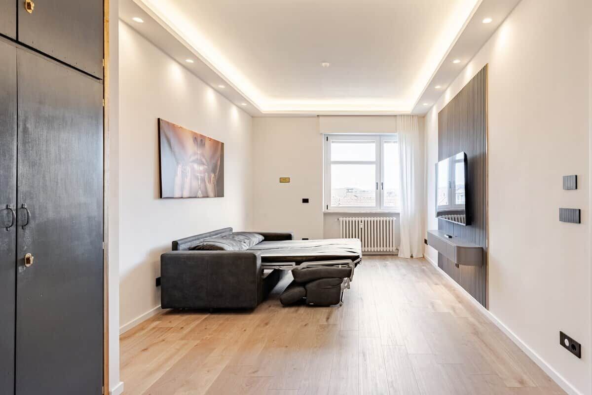 Ein modernes Hotelzimmer mit Bett, Flachbildfernseher und einem fensterbelaubten Fenster.