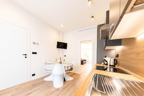 Una cocina moderna con estufa integrada, cafetera y comedor con mesa y sillas.