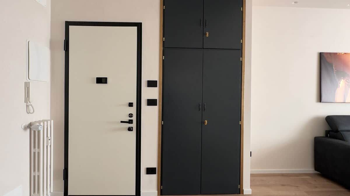 Een kamer met een witte deur, een zwarte garderobe, een radiator en een zwarte bank.
