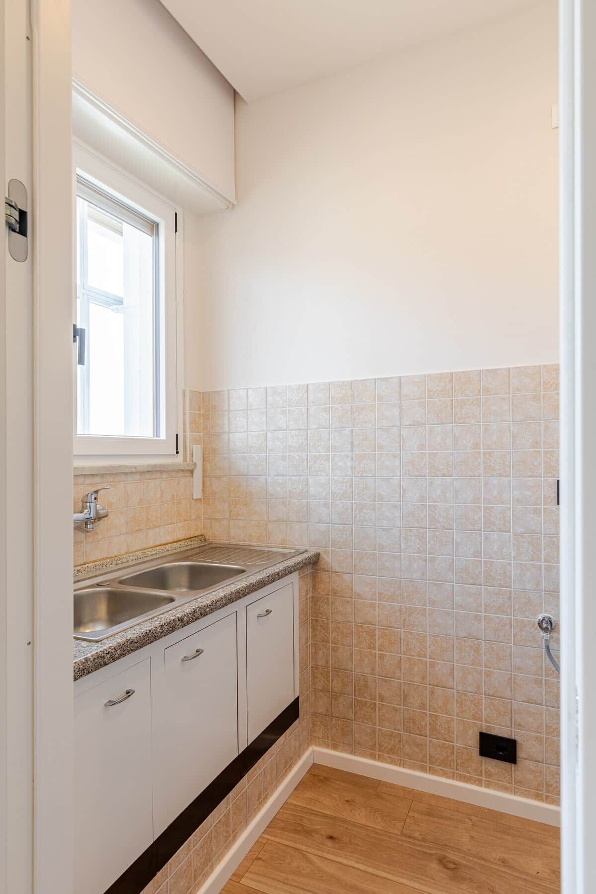 A kitchen with a window, a sink, and cabinets.