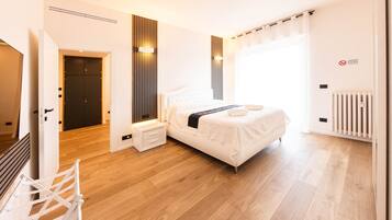 Een moderne slaapkamer met een bed, nachtkastjes, een radiator en een deur die naar een andere kamer leidt.