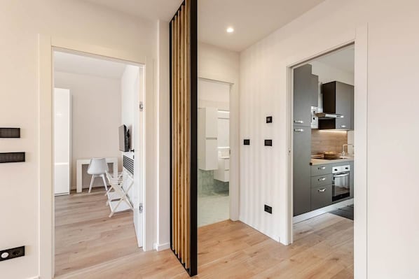 Un interior moderno con piso de madera, una cocina con armarios grises y un área de comedor blanca.