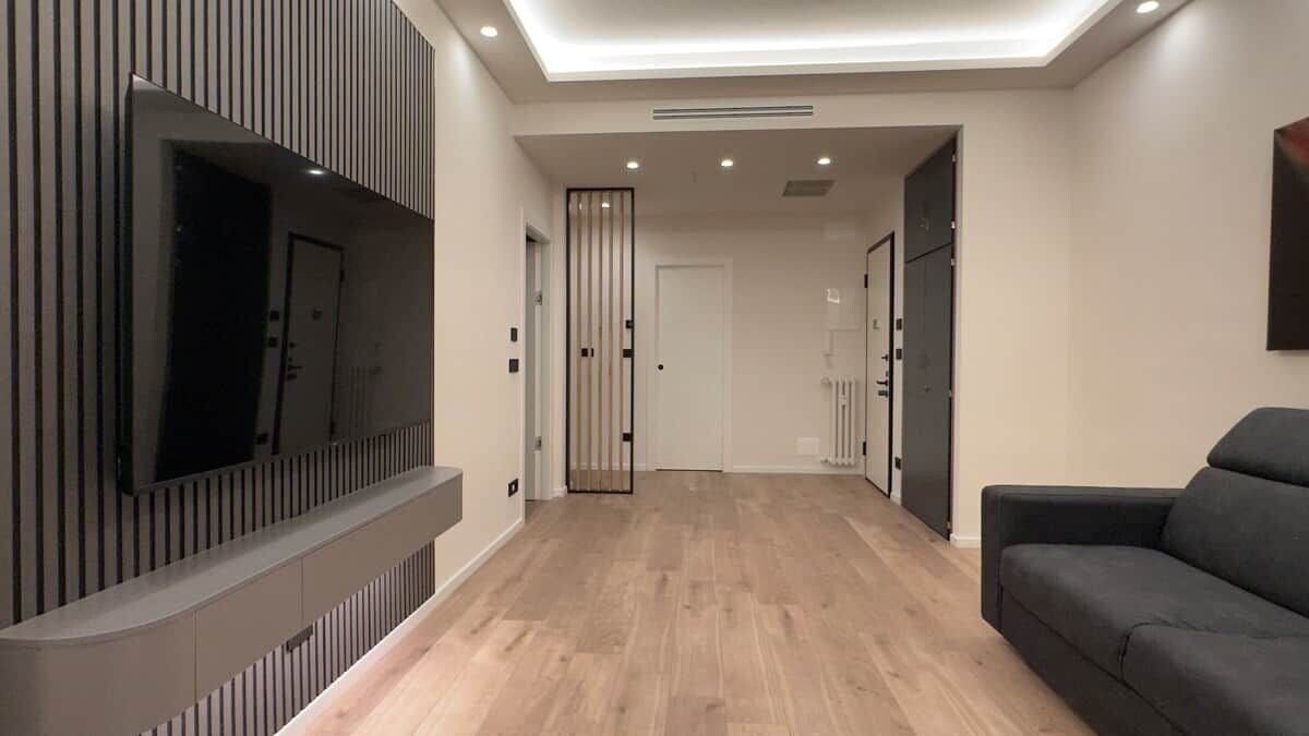 Een moderne woonkamer met een flatscreen televisie aan de wand, een bank en een houten vloer.