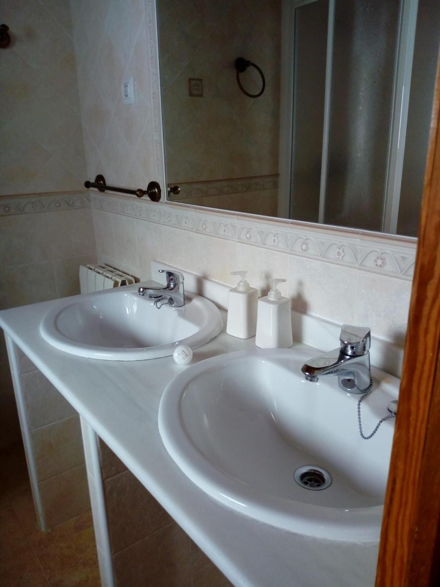 A bathroom with two sinks, a mirror, and a towel rack.