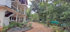 A pathway leading to a building with a covered porch and a garden area with potted plants. - Studio Arambol Escape R8 Couple Friendlly (Arambol)