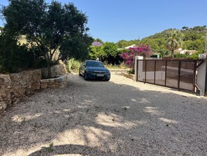 A gravel driveway leading to a gated entrance with a parked car. - New traditional-style villa just a stone's throw from a beautiful cove (Jávea)