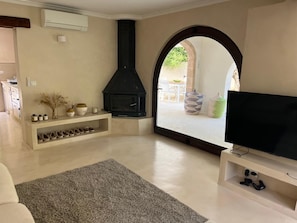 A living room with a fireplace, a television, and a view through an archway. - New traditional-style villa, just a stone's throw from a beautiful cove   (Jávea)
