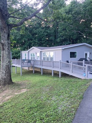 A single-story mobile home with a fenced deck, surrounded by trees. - Country life,come and relax! (Crossville)