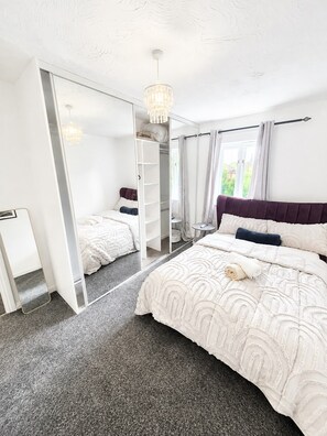 A bedroom with a bed, a wardrobe, a mirror, and a chandelier. - Elegant 2 Bedroom Apartment in Erith Breathtaking River Thames View (Erith)