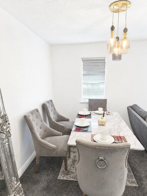 A dining area with a marble table, upholstered chairs, and a chandelier. - Elegant 2 Bedroom Apartment in Erith Breathtaking River Thames View (Erith)