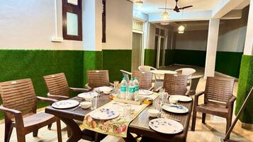 Uma sala de jantar com uma mesa posta para seis pessoas, rodeada por cadeiras, com um ventilador de teto e luminárias pendentes.