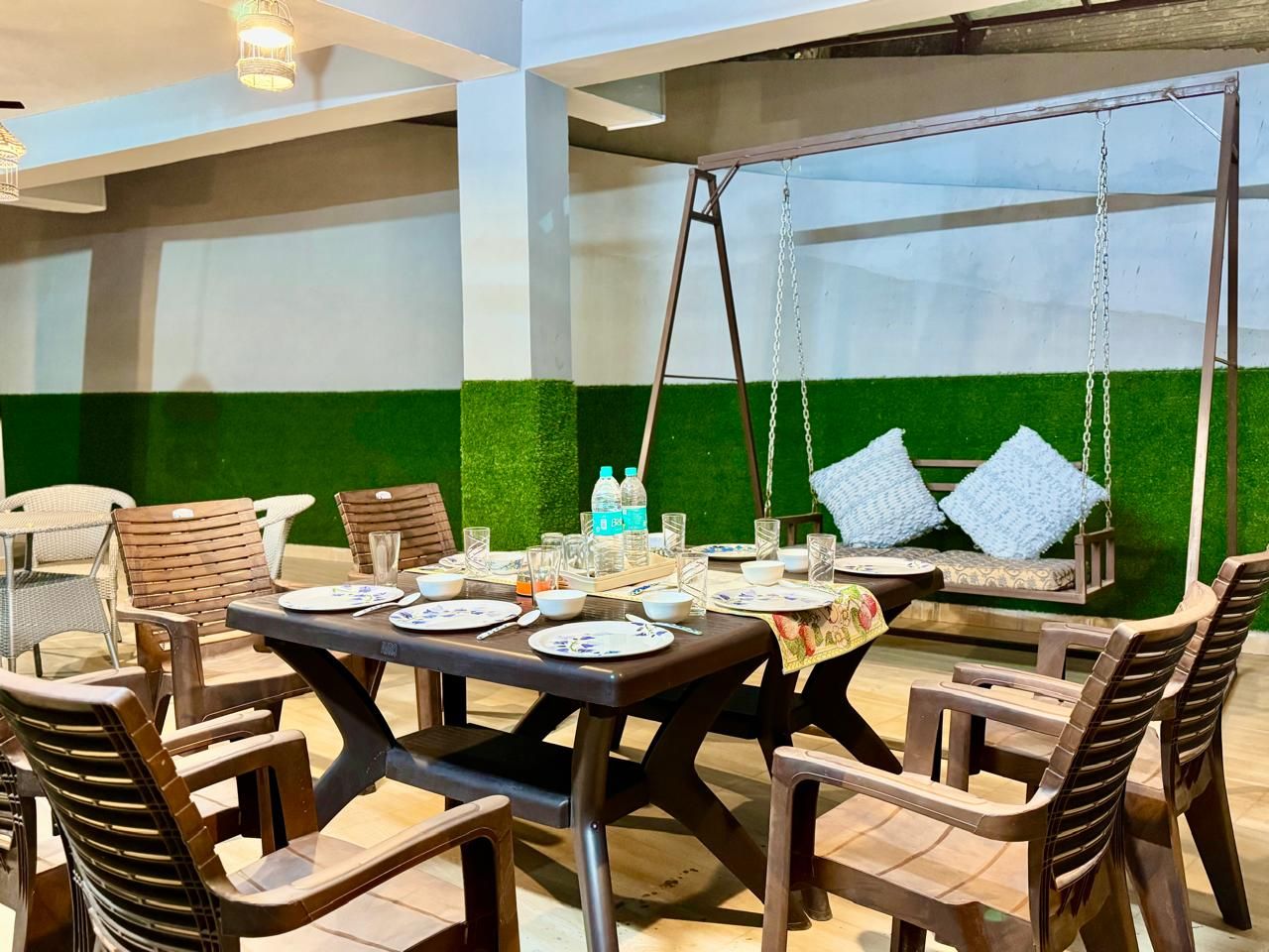 A dining area with a round table set for four, surrounded by wicker chairs.