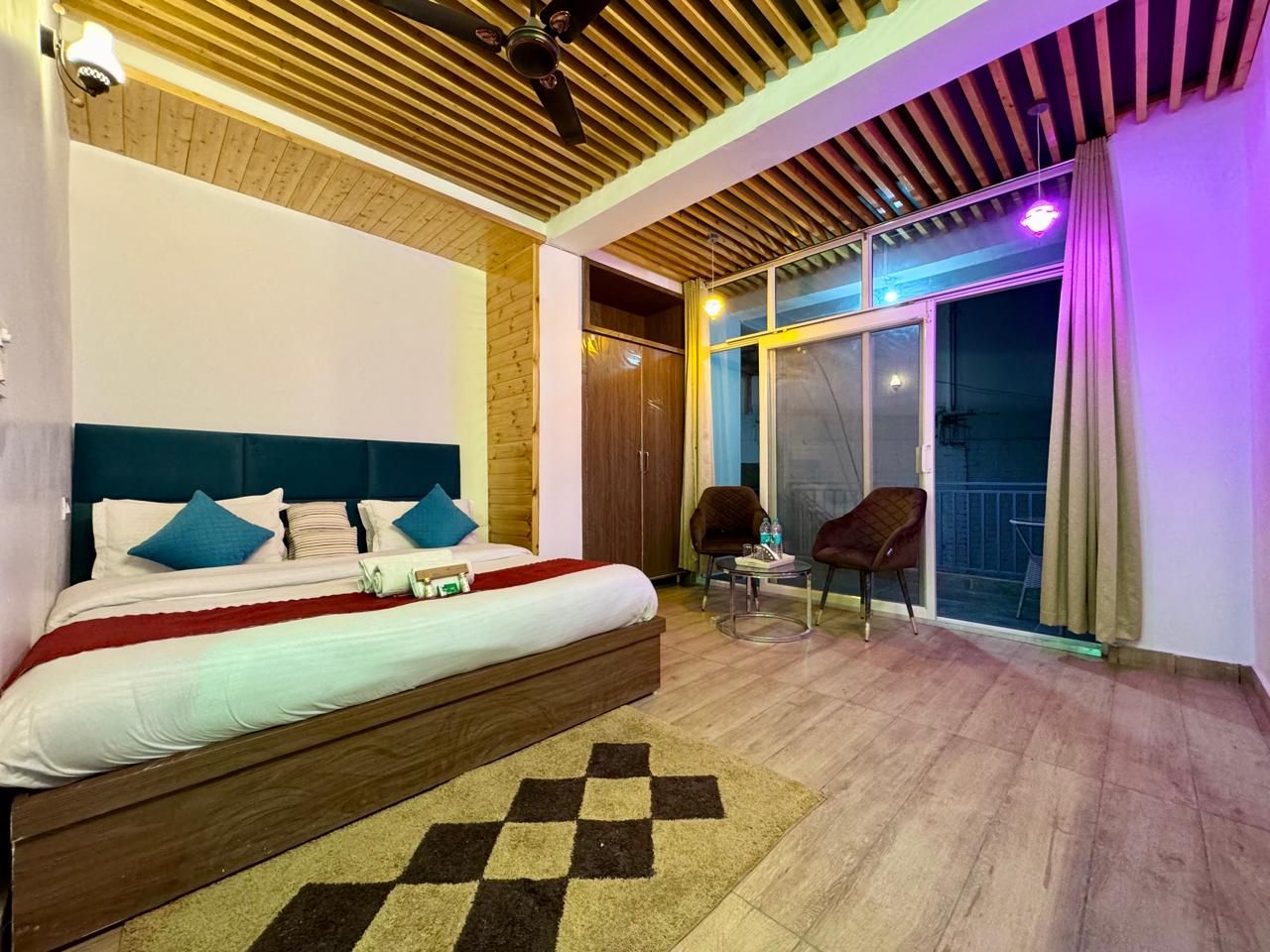 Un dormitorio con cama, una silla, una mesita y vistas al exterior.
