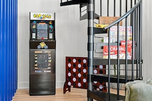 A Pac-Man arcade machine, a bookshelf with magazines, and a polka dot chair. - Modern 4BR Container Home | Epic Private Rooftop (Pittsburgh)
