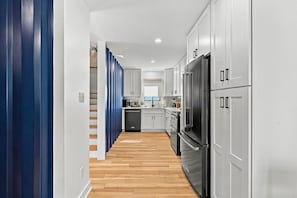 A modern kitchen with white cabinetry, a stainless steel refrigerator, and a dishwasher. - Modern 4BR Container Home | Epic Private Rooftop (Pittsburgh)