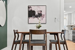A dining area with a table and chairs, a framed artwork on the wall, and a plant on the table. - Modern 4BR Container Home | Epic Private Rooftop (Pittsburgh)