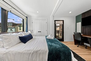 A modern bedroom with a large bed, a desk, and a view of the outside. - Modern 4BR Container Home | Epic Private Rooftop (Pittsburgh)