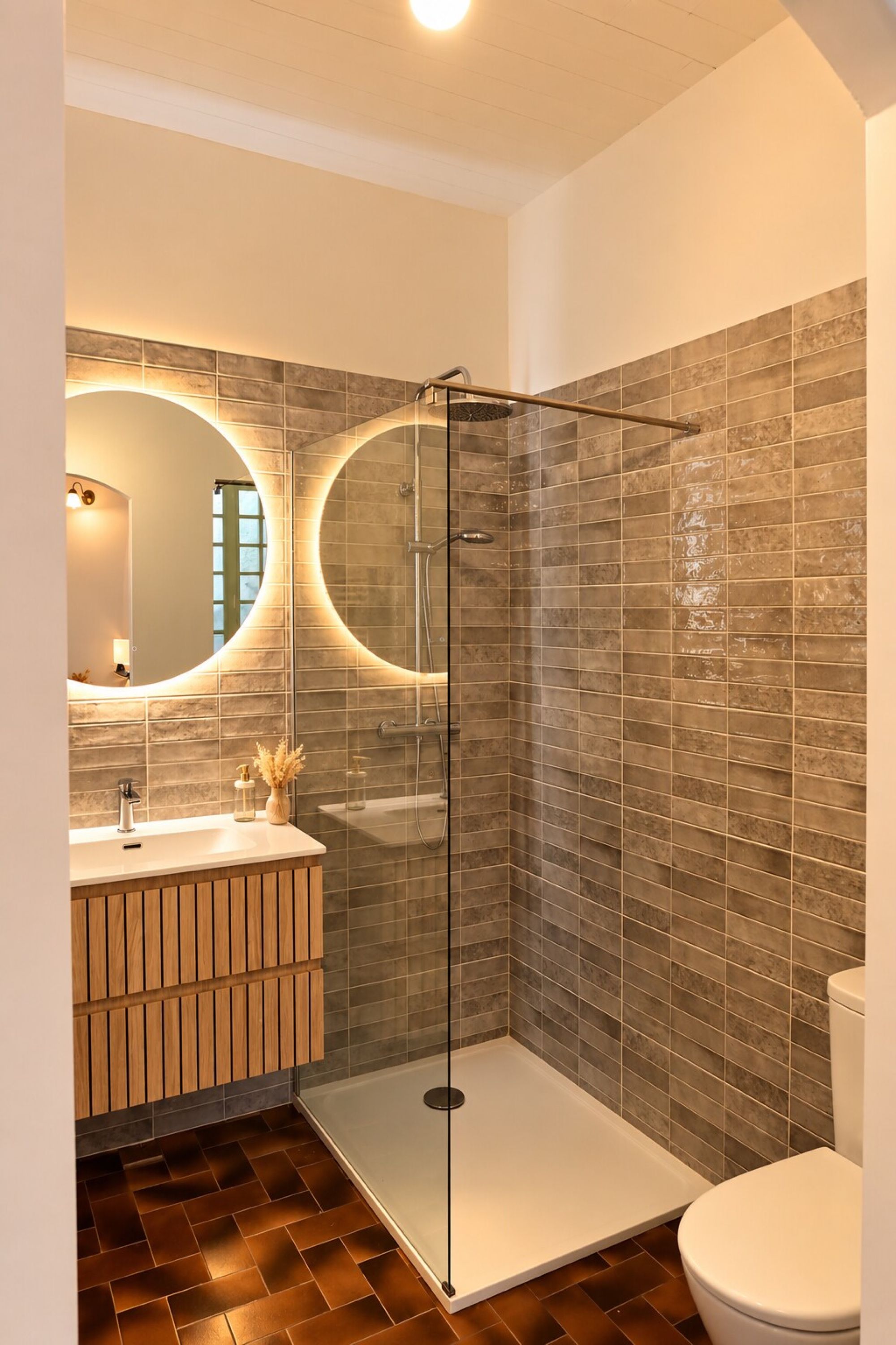 Een moderne badkamer met een douchecabine van glas, een houten wastafelmeubel en een toilet.
