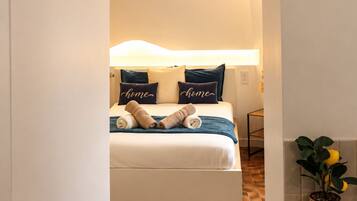 A hotel room with a bed, a bedside table, a lamp, and a potted plant.