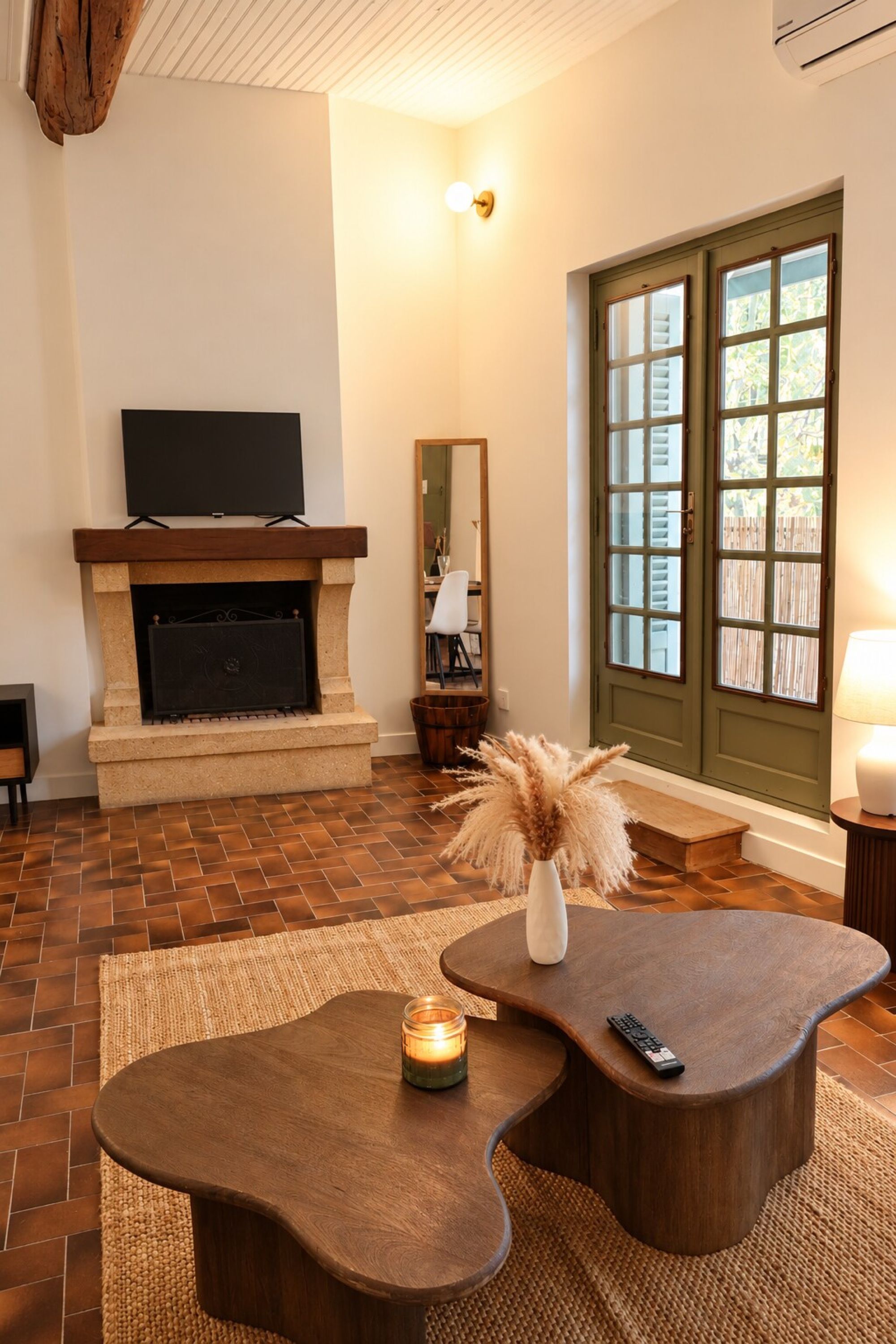 A living room with a fireplace, television, and a large window with blinds.