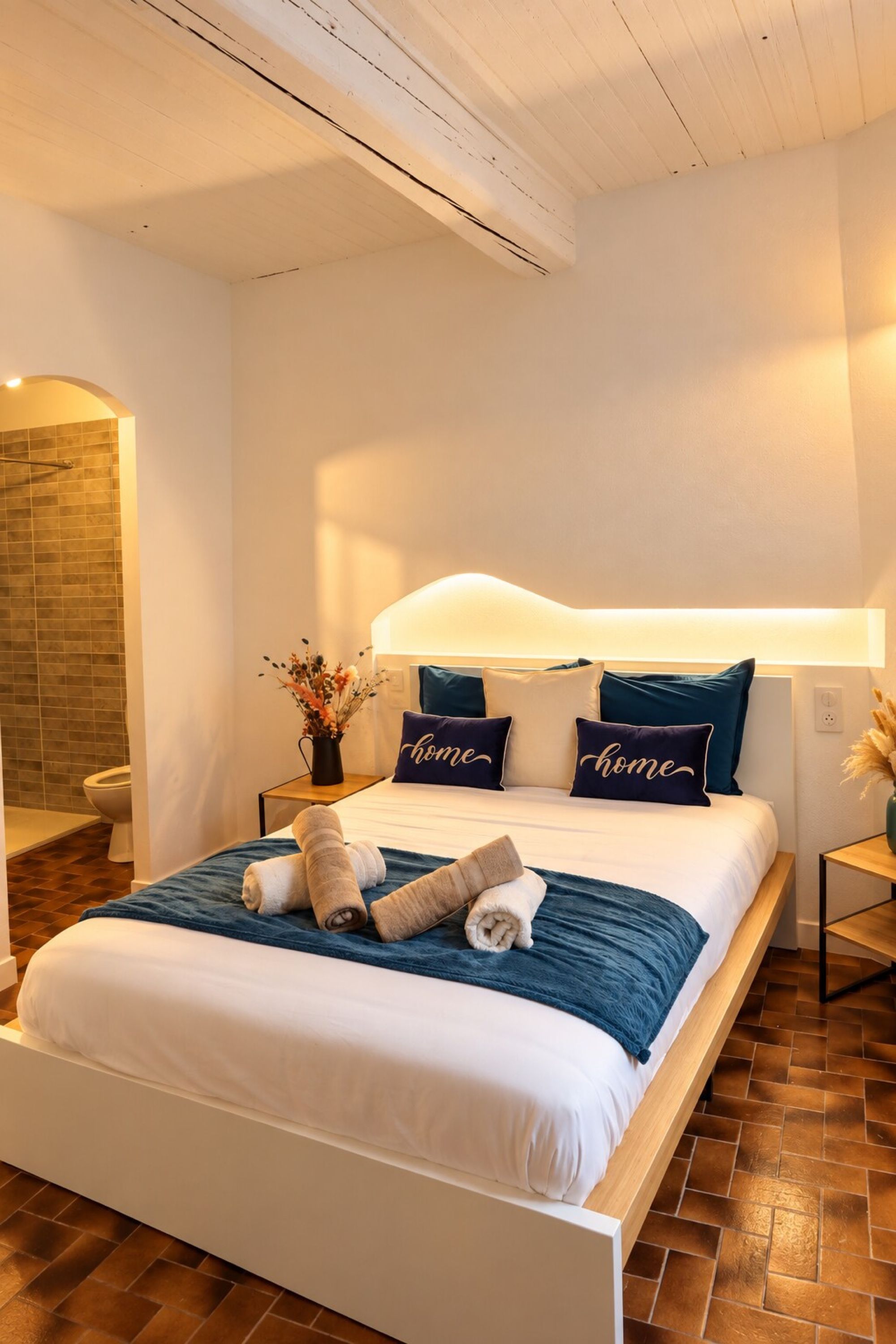 Une chambre moderne avec un grand lit, une table de chevet, une commode et une lampe fixée au mur.